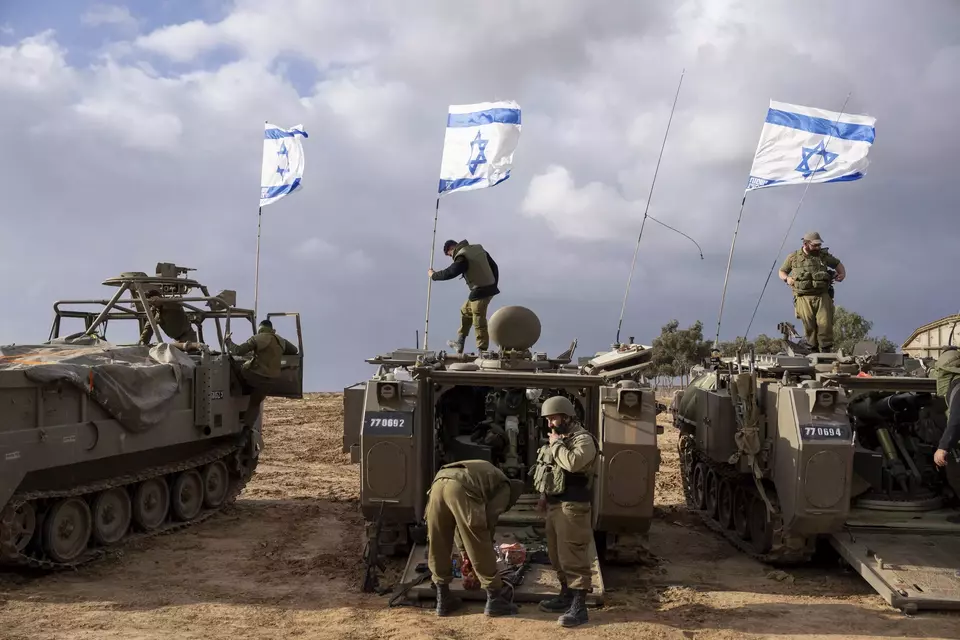 Tentara Israel beraktivitas di dekat kendaraan militer lapis baja di sepanjang perbatasan Israel dengan Jalur Gaza, di Israel selatan, pada Senin, 20 November 2023. 

