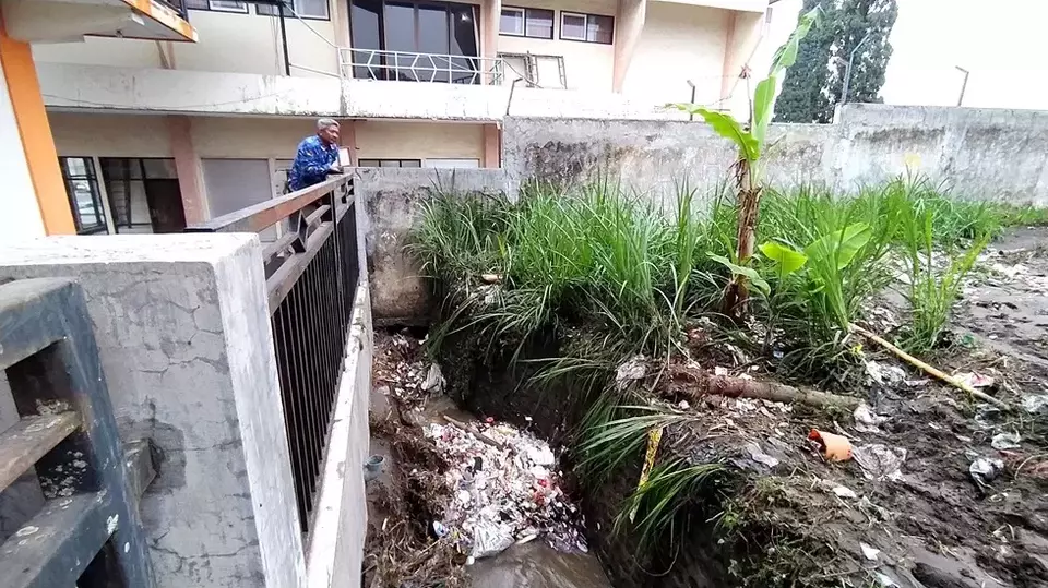 Tumpukan sampah menyumbat aliran sungai menyebabkan luberan air menerjang jalan raya di Pujon, Malang. 