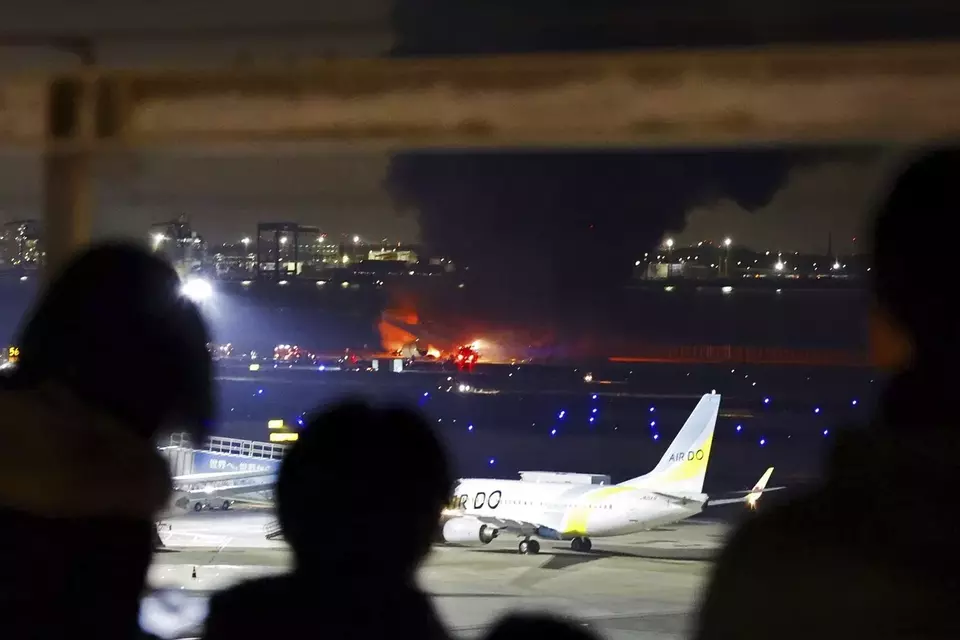 Orang-orang menyaksikan pesawat Japan Airlines terbakar di landasan Bandara Haneda pada Selasa malam, 2 Januari 2024 di Tokyo, Jepang. 
