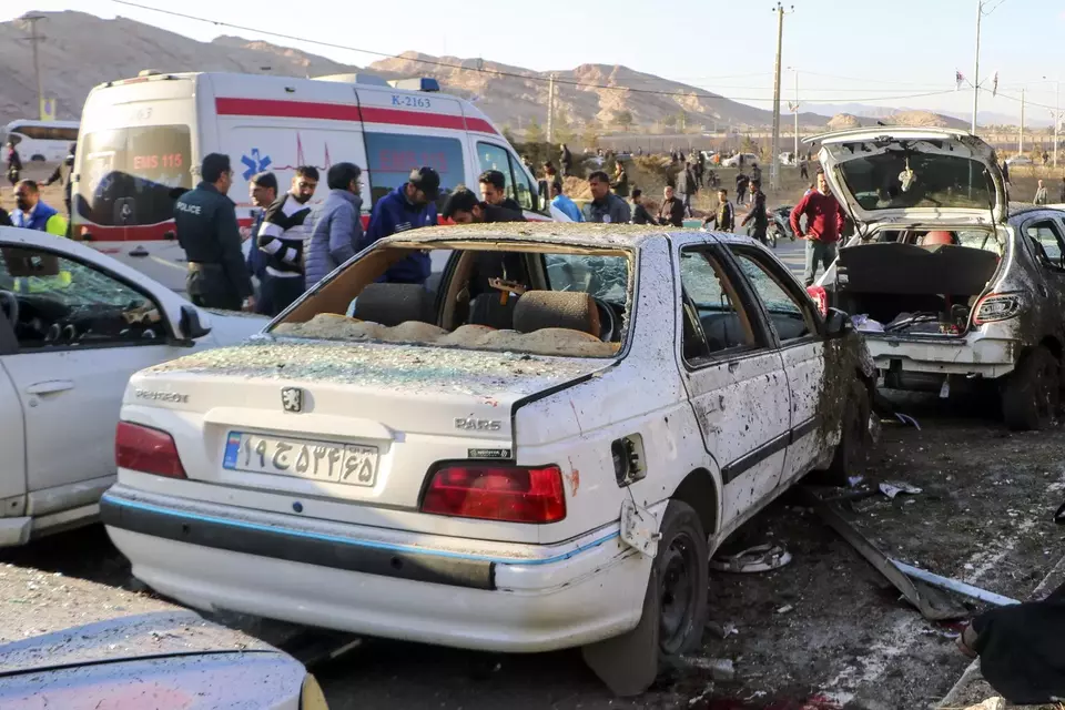 Warga Iran berkumpul di samping mobil yang hancur setelah terjadinya ledakan bom di Kerman, Iran, Rabu, 3 Januari 2024.
