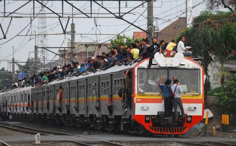 Sejumlah penumpang berada di atap KRL jurusan Jakarta-Bogor di perlintasan kereta Bukit Duri, Jakarta, Selasa (18/10). Hujan lebat menyebabkan gangguan sinyal sehingga menelantarkan ratusan penumpang