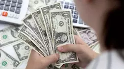 Seorang wanita memegang lembaran uang kertas dolar Amerika Serikat (AS) pada 30 Mei 2022. (FOTO: REUTERS/DADO RUVIC)