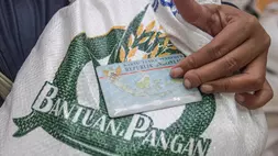 Seorang warga memegang KTP saat mengambil beras bantuan pangan dari Perum Bulog di Kebon Kosong, Kemayoran, Jakarta, baru-baru ini. (ANTARA FOTO/Zaky Fahreziansyah/app)