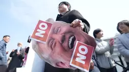 Seorang pria memegang gambar Presiden AS Donald Trump, usai konferensi pers bersama para demonstran menolak seruan Trump agar negara-negara sekutu mengirimkan kapal perang untuk menjaga Selat Hormuz tetap terbuka. Unjuk rasa dilakukan dekat Kedubes AS di Seoul, Korea Selatan, pada Senin (16/03/2026). 