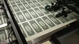 Lembaran uang kertas satu dolar melewati mesin cetak di Biro Pengukiran dan Percetakan di Washington, AS.