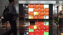 Pekerja melintasi layar pergerakan saham di gedung Bursa Efek Indonesia (BEI), Jakarta. (Investor Daily/David Gita Roza)
