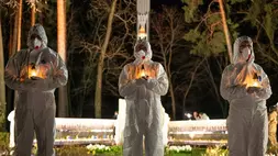 Orang-orang yang mengenakan pakaian pelindung putih memegang lilin selama upacara peringatan yang didedikasikan untuk petugas pemadam kebakaran dan pekerja yang meninggal setelah bencana nuklir Chernobyl (Chornobyl) pada 1986, menjelang peringatan 40 tahunnya di Slavutych, Ukraina, Sabtu (25/4/2026). Chernobyl adalah nama Ukraina untuk kota tersebut. (FOto: AP/ Dan Bashakov)