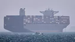 Sebuah kapal kontainer berlabuh sementara sebuah perahu motor kecil melintas di latar depan di Selat Hormuz di lepas pantai Bandar Abbas, Iran, Sabtu (2/5/2026). (Foto: Amirhosein Khorgooi/ ISNA via AP)