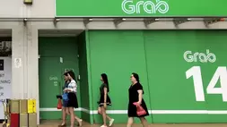 Para pekerja kantoran berjalan melewati logo Grab Holdings Ltd. di Singapura. (Foto: AP/ Wong Maye)