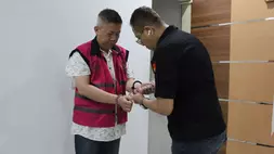Petugas Kejati DKI Jakarta memasang borgol terhadap pengusaha asal Malang berinisial LHL alias Ko Xiong, tersangka korupsi kredit. 