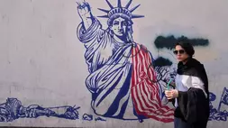 Seorang wanita berjalan melewati mural anti-Amerika di dinding bekas Kedutaan Besar AS, yang sekarang menjadi museum, di Teheran, Iran pada Jumat (12/6/2026). (Foto: AP/ Vahid Salemi)
