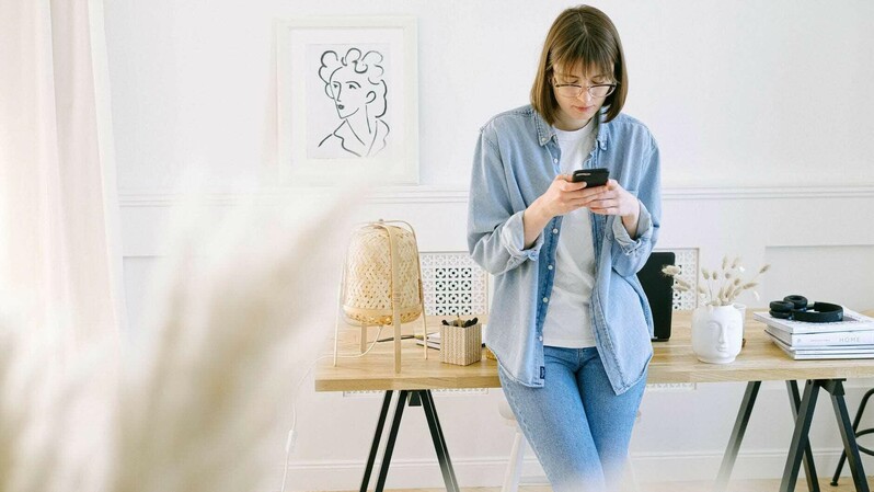 Ilustrasi seorang perempuan sedang menggunakan aplikasi transfer bank di smartphone.