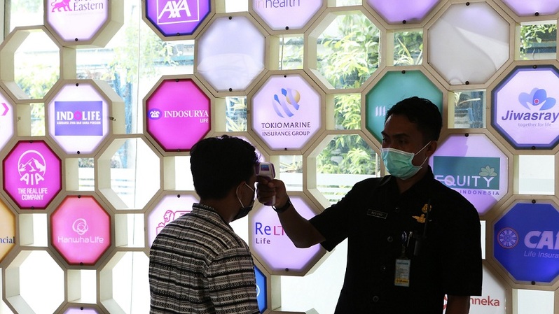 Petugas periksa suhu tubuh pengunjung di kantor AAJI di Jakarta, belum lama ini. Foto ilustrasi: Beritasatu Photo/Uthan AR