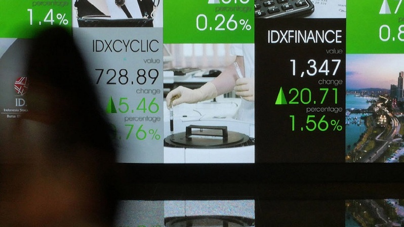 Pekerja melintasi layar pergerakan saham di gedung BEI, Jakarta. Foto ilustrasi: Investor Daily/David Gita Roza