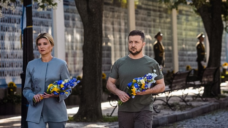 Presiden Ukraina Volodymyr Zelensky (kanan) dan istrinya Olena menghadiri upacara peringatan di dinding peringatan yang menampilkan gambar prajurit Ukraina dan prajurit wanita yang terbunuh sejak Rusia meluncurkan serangan, pada 24 Agustus 2022. (FOTO: UKRAINE PRESIDENCY / AFP)