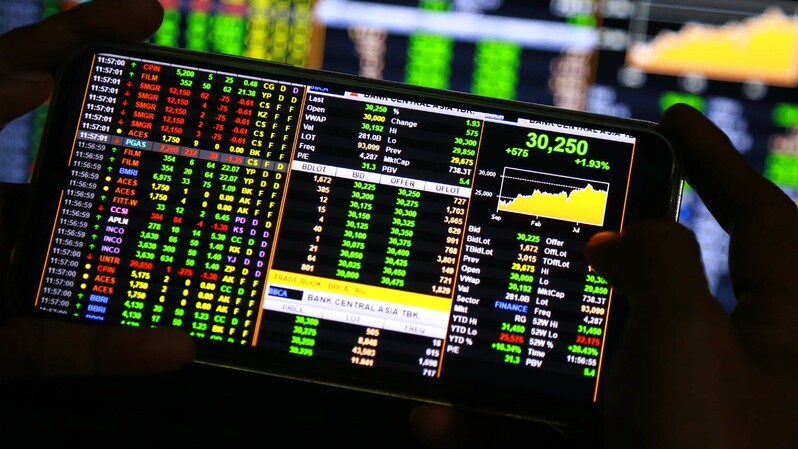 Pengguna telepon seluler melihat pergerakan harga saham. (BeritaSatu Photo/Mohammad Defrizal)