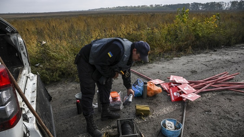Seorang anggota unit pembersihan ranjau Ukraina memeriksa peralatannya di dekat Izyum, Ukraina timur pada 1 Oktober 2022 di tengah serangan Rusia ke Ukraina. (FOTO: Juan BARRETO / AFP)