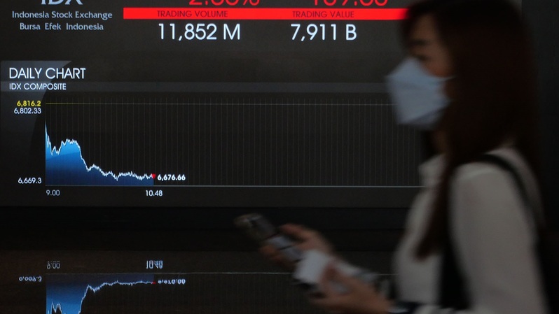 Pekerja melintasi layar pergerakan saham di gedung BEI, Jakarta. (B Universe Photo/David Gita Roza)