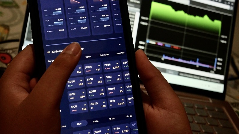 Investor memantau pergerakan saham melalui aplikasi. (B Universe Photo/David Gita Roza)