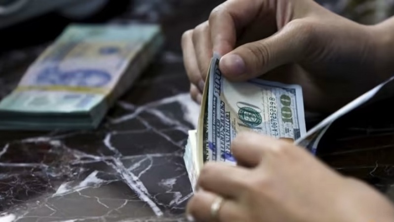 Seorang karyawan menghitung uang kertas dolar Amerika Serikat (AS) di dekat uang kertas dong Vietnam di sebuah bank di Hanoi, Vietnam pada 12 Agustus 2015. (Foto: REUTERS/Kham)