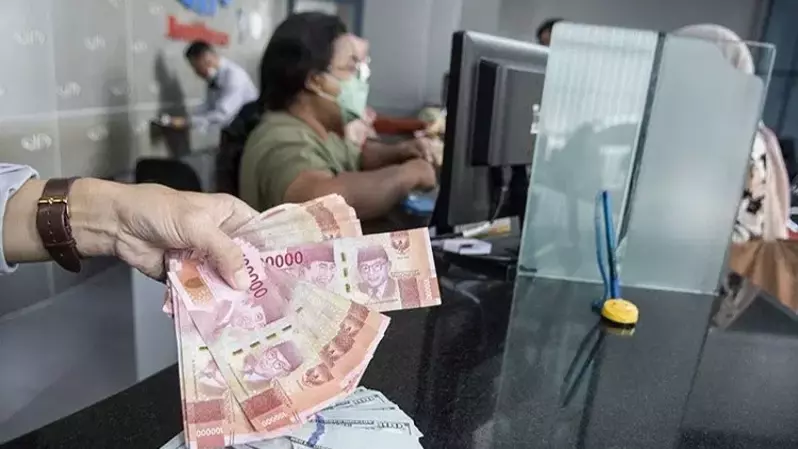 Petugas menunjukan uang pecahan rupiah dan dolar AS di gerai penukaran mata uang asing (Valuta Inti Prima) VIP Money Changer, Jakarta pada 3 Januari 2023. (Foto: ANTARA FOTO/Muhammad Adimaja/foc/aa)