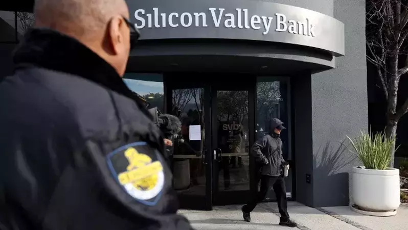 Seorang satpam mengawasi seorang pelanggan meninggalkan kantor Silicon Valley Bank pada 13 Maret 2023 di Santa Clara, California, Amerika Serikat (AS). Beberapa hari setelah Silicon Valley Bank bangkrut, pelanggan mengantre untuk mencoba dan mengambil kembali dana mereka. (Foto: Justin Sullivan/Getty Images/AFP)