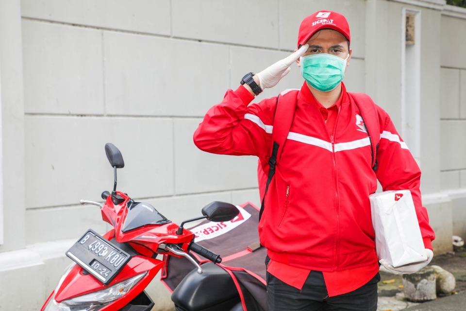 Kurir SiCepat Ekspres menggunakan masker saat melakukan pengantaran paket.