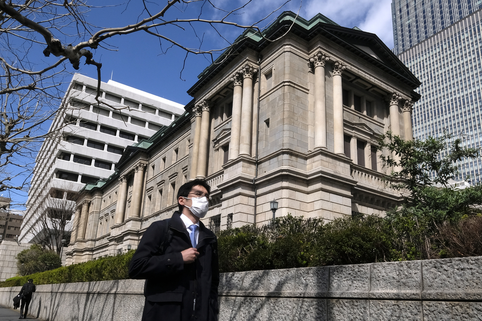 Seorang pejalan kaki yang mengenakan masker sedang berjalan melewati kantor pusat Bank of Japan (BoJ) di Tokyo, Jepang beberapa waktu lalu. (FOTO: Kazuhiro NOGI / AFP)