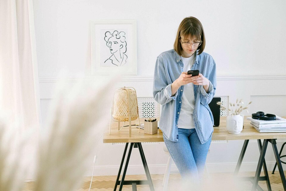 Ilustrasi seorang perempuan sedang menggunakan aplikasi transfer bank di smartphone.