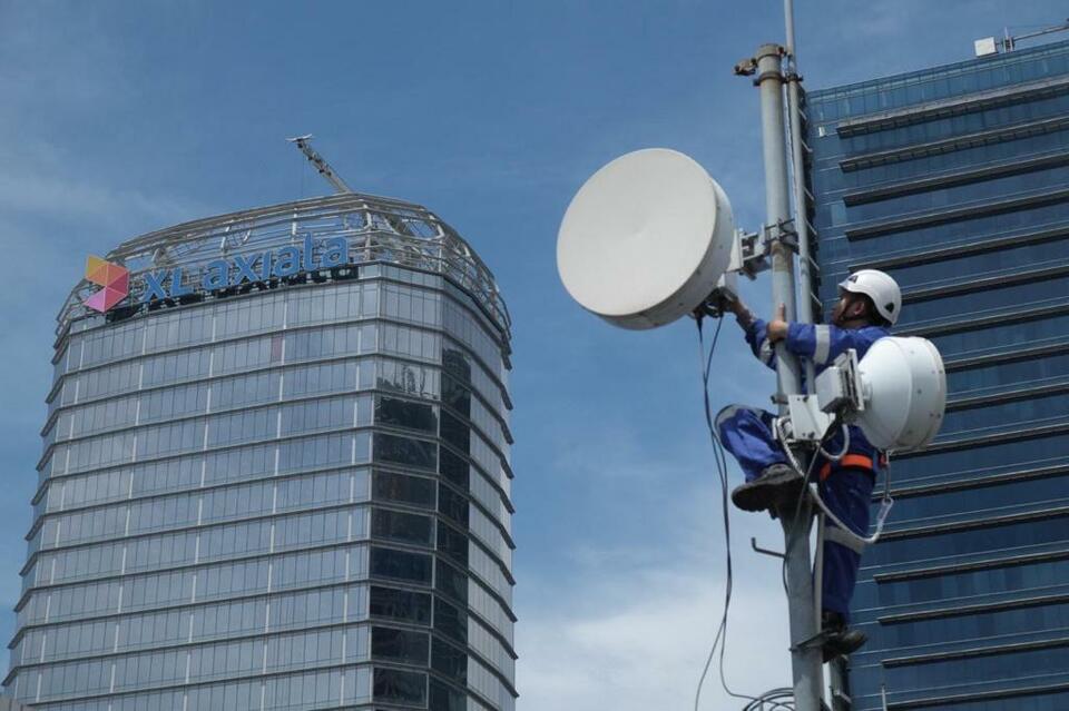 Teknisi merawat BTS dengan latar belakang Gedung XL Axiata di Jakarta. (Ilustrasi/Ist)   