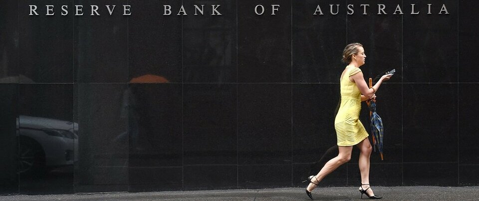 Seorang wanita melewati plang nama bertuliskan Reserve Bank Australia yang terpampang pada dinding gedung. ( Foto: William West / AFP / Getty Images )