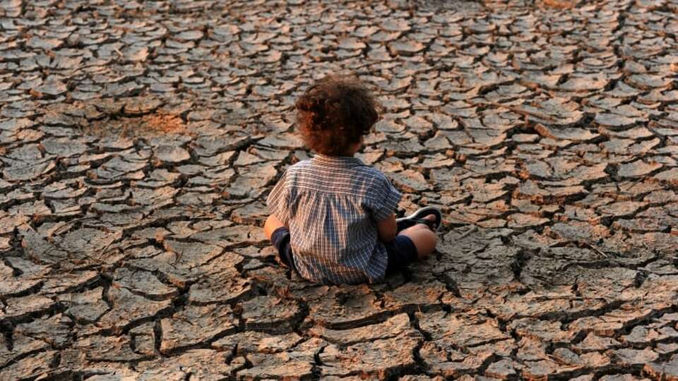 Seorang anak duduk di atas tanah yang terkena dampak kekeringan, di pinggiranTegucigalpa, Honduras selatan pada 2016. Para ahli mengatakan kekeringan bisa menjadi efek samping dari perubahan iklim. ( Foto: Orlando Sierra / AFP / Getty Images )