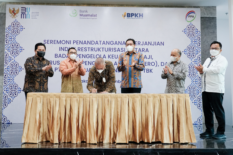 Menteri BUMN Erick Thohir (kiri) bersama Staf Ahli Wakil Presiden Iggi Haruman Achsien (kanan) dan Komisaris Utama PT Bank Muamalat Indonesia Tbk Ilham Habibie (kedua kanan) menyaksikan penandatanganan Master Restructuring Agreement (MRA) oleh Direktur Utama PT Perusahaan Pengelola Aset (Persero) Yadi Jaya Ruchandi (kedua kiri), Anggota Badan Pelaksana BPKH A Iskandar Zulkarnain (ketiga kiri), dan Direktur Utama PT Bank Muamalat Indonesia Tbk Achmad K Permana (ketiga kanan). 