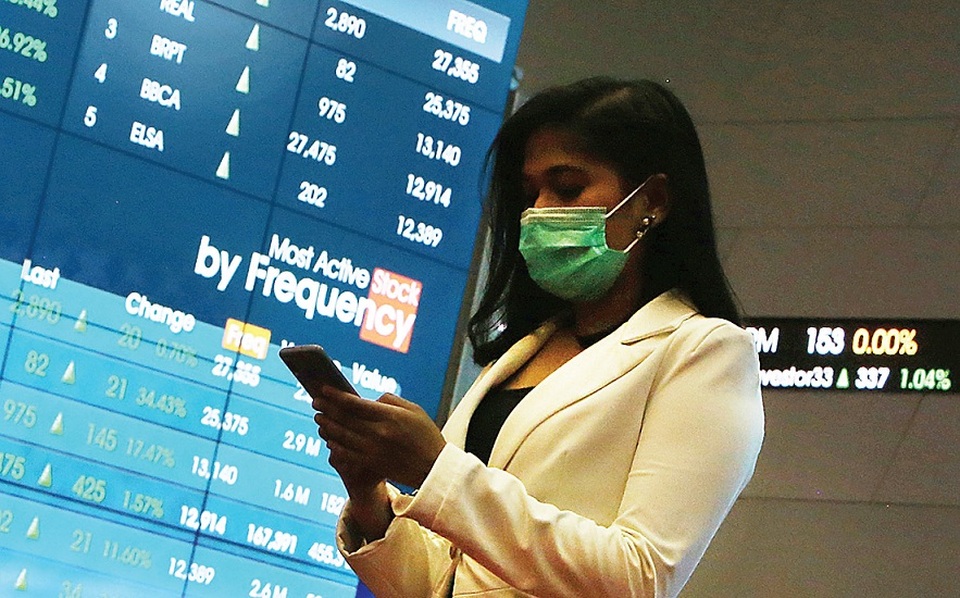 Karyawan menggunakan ponsel di depan monitor saham di Bursa Efek Indonesia, Jakarta. Foto ilustrasi:  Beritasatu Photo/Uthan AR