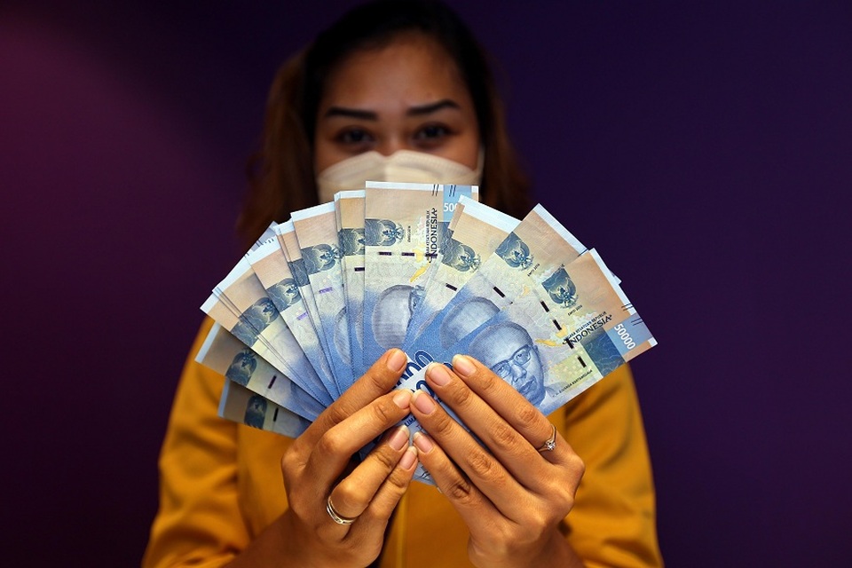 Karyawati memperlihatkan uang rupiah di salah satu bank di Jakarta. Foto ilustrasi: BeritaSatu Photo/Mohammad Defrizal