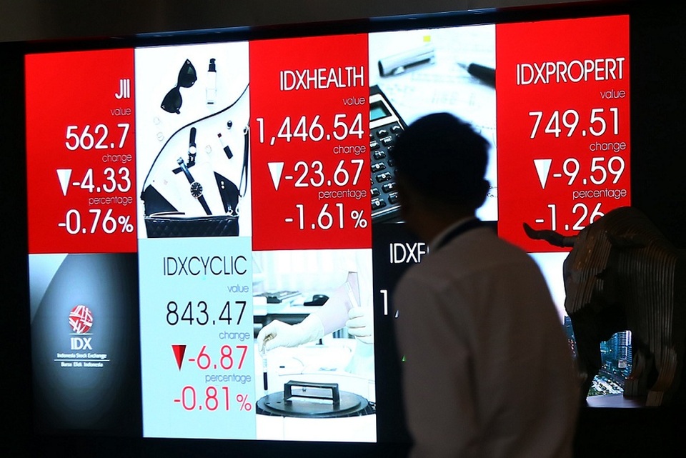 Karyawan melintas di depan layar elektronik yang menampilkan pergerakan harga saham di Bursa Efek Indonesia (BEI) di Jakarta.  Foto ilustrasi:  BeritaSatu Photo/Mohammad Defrizal