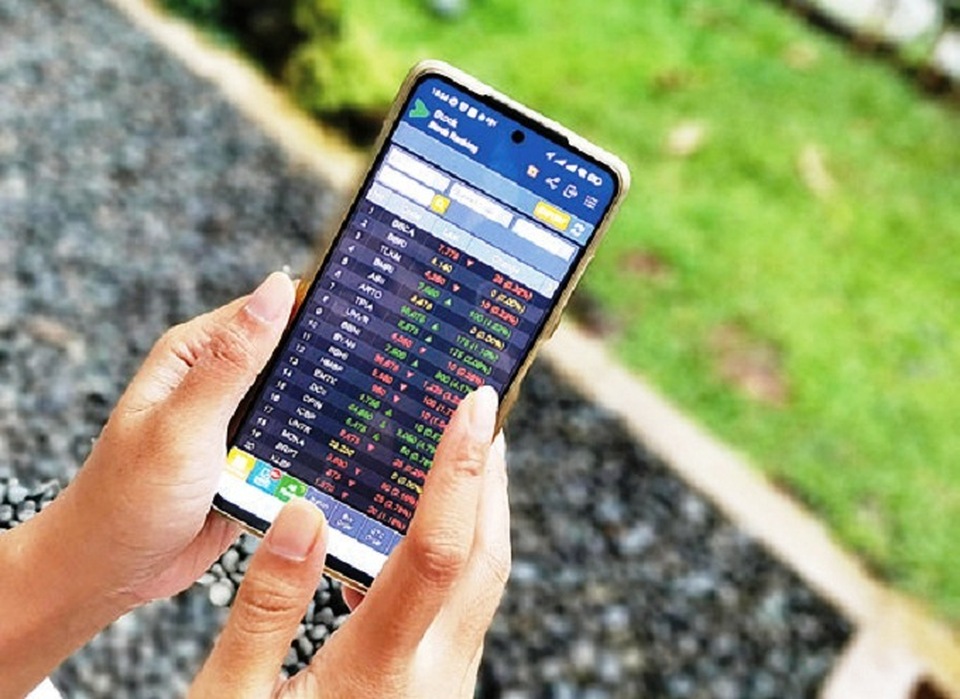 Trader memperhatikan pergerakan harga saham melalui ponselnya, pekan lalu. Foto ilustrasi: Investor Daily/David Gita Roza