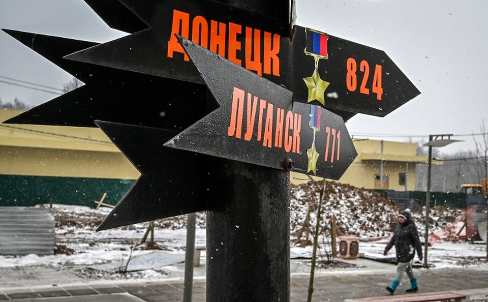 Seorang wanita berjalan melewati tanda-tanda yang menunjukkan arah ke Donetsk dan Luhansk, wilayah separatis Ukraina, sebagai bagian dari apa yang disebut 'instalasi rakyat untuk tentara Rusia', dibuat oleh penduduk di halaman belakang gedung apartemen di Podolsk, luar wilayah Moskow, pada 28 Maret 2022. (FOTO: YURI KADOBNOV / AFP)