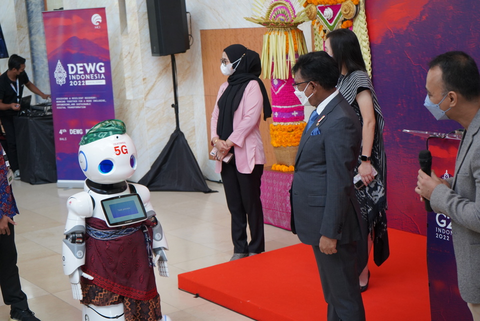 Menteri Komunikasi dan Informatika Johnny G. Plate saat berinteraksi dengan Artificial Intelligence (AI) Robot serta memantau beberapa showcase 5G Telkomsel pada kegiatan DEWG ke-4 di Bali. (Foto: Dok.PR)