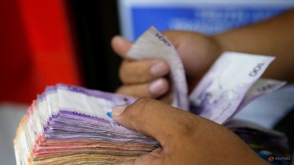 Seseorang menghitung segepok uang Peso Filipina yang diterimanya dari kerabat di pusat pengiriman uang di Makati City, Metro Manila, Filipina pada 19 September 2018. (FOTO: Reuters/Eloisa Lopez)