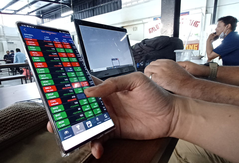 Investor memantau pergerakan saham lewat ponsel. (B Universe Photo/Uthan AR) 