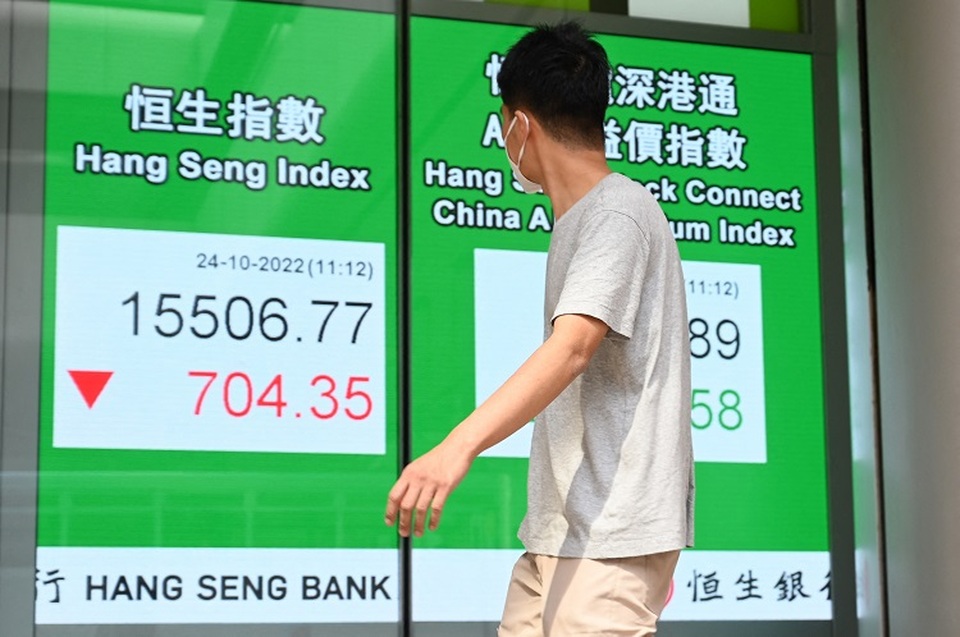Seorang pejalan kaki melewati tanda yang menunjukkan angka-angka untuk Indeks Hang Seng di Hong Kong pada 24 Oktober 2022. (Foto: Peter PARKS / AFP)