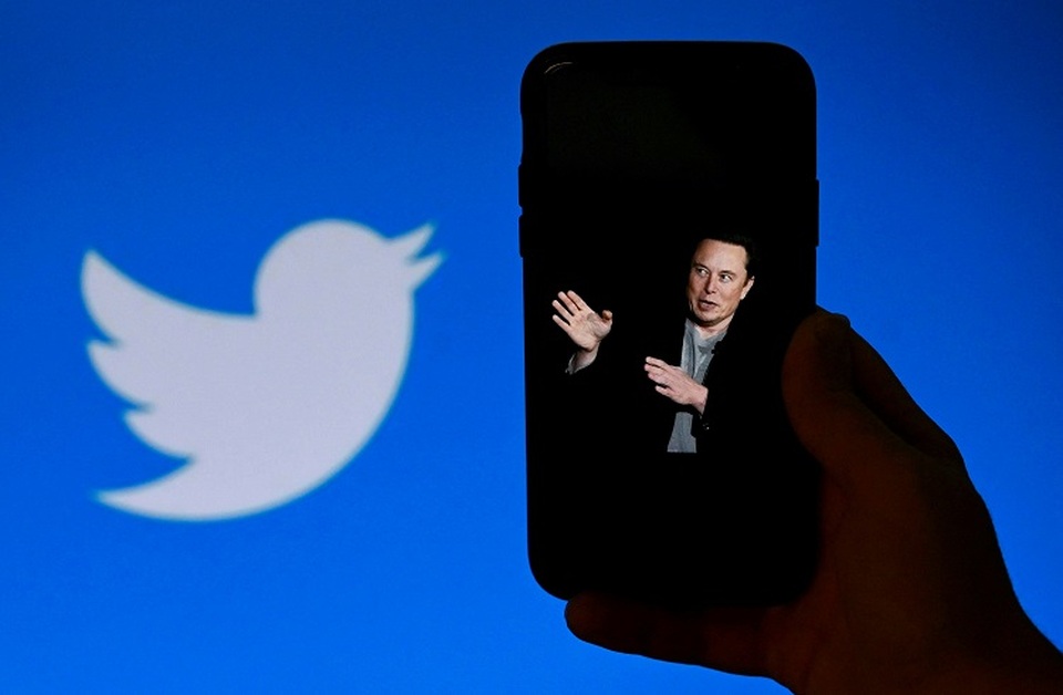 Ilustrasi Elon Musk dengan ponsel Apple dengan logo Twitter di latar belakang. (FOTO: OLIVIER DOULIER / AFP)