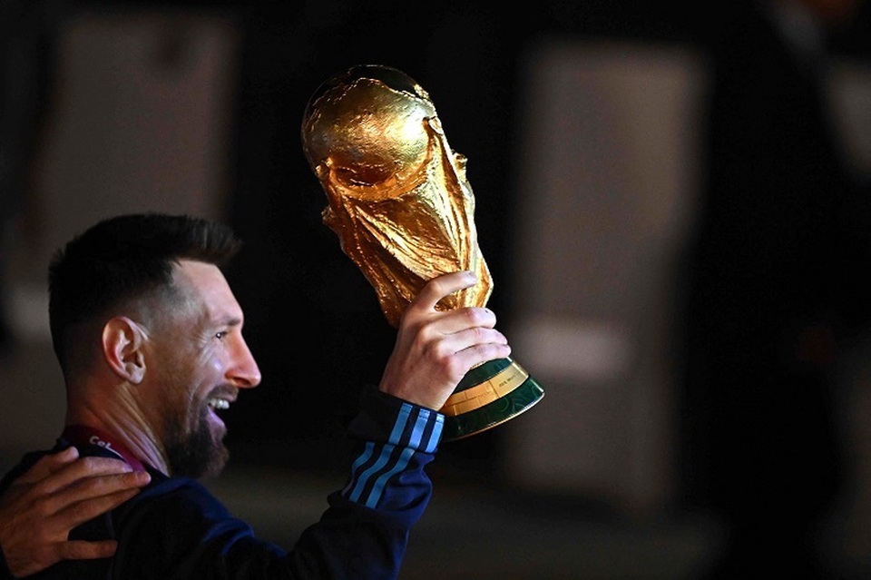 Kapten dan penyerang tim nasional Argentina Lionel Messi memegang Trofi Piala Dunia FIFA setibanya di Bandara Internasional Ezeiza setelah memenangkan turnamen Piala Dunia Qatar 2022 di Ezeiza, Provinsi Buenos Aires, Argentina pada 20 Desember 2022. (Foto: Luis ROBAYO / AFP)