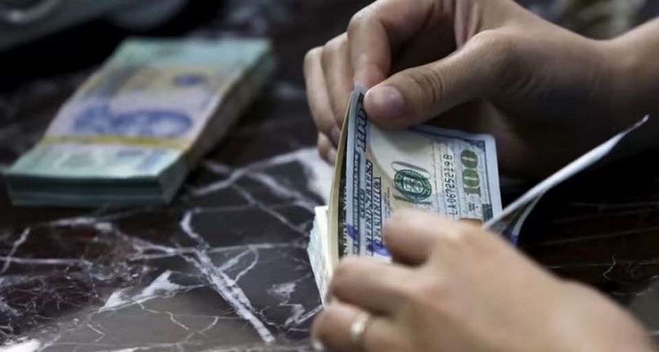 Seorang karyawan menghitung uang kertas dolar Amerika Serikat (AS) di dekat uang kertas dong Vietnam di sebuah bank di Hanoi, Vietnam pada 12 Agustus 2015. (Foto: REUTERS/Kham)