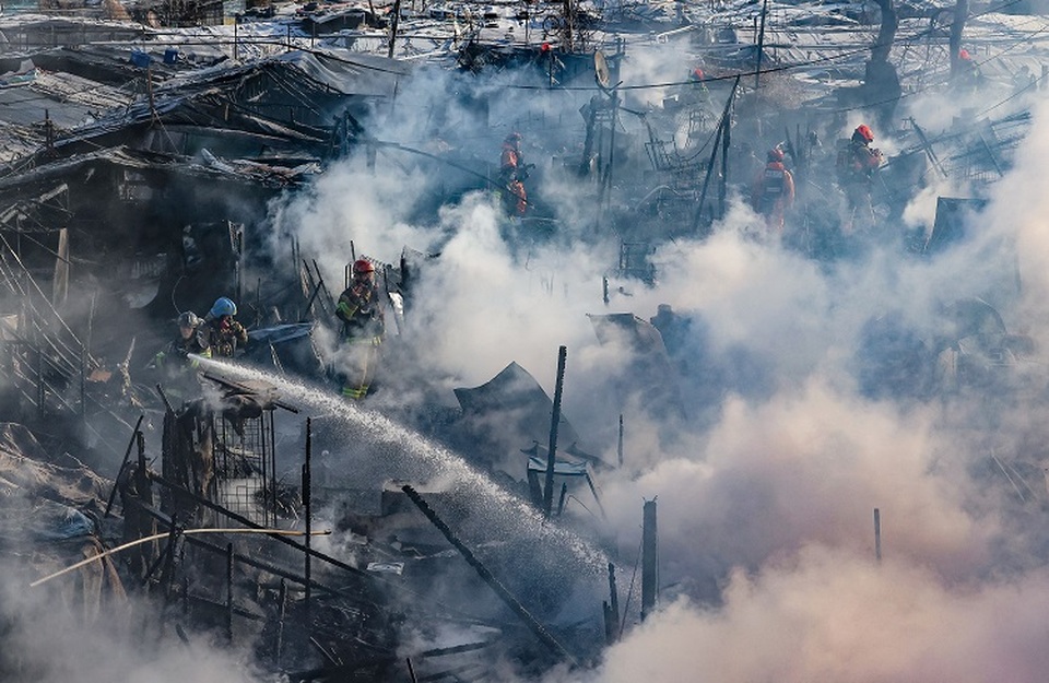 Petugas pemadam kebakaran berusaha memadamkan api di Desa Guryong, salah satu daerah kumuh terakhir Korea Selatan (Korsel) yang tersisa, di selatan Seoul pada 20 Januari 2023. (FOTO: YONNAP / AFP)