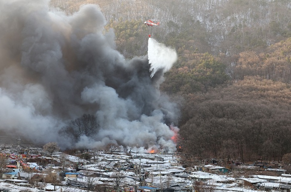 Petugas pemadam kebakaran berusaha memadamkan api di Desa Guryong, salah satu daerah kumuh terakhir Korea Selatan (Korsel) yang tersisa, di selatan Seoul pada 20 Januari 2023. (FOTO: YONNAP / AFP)