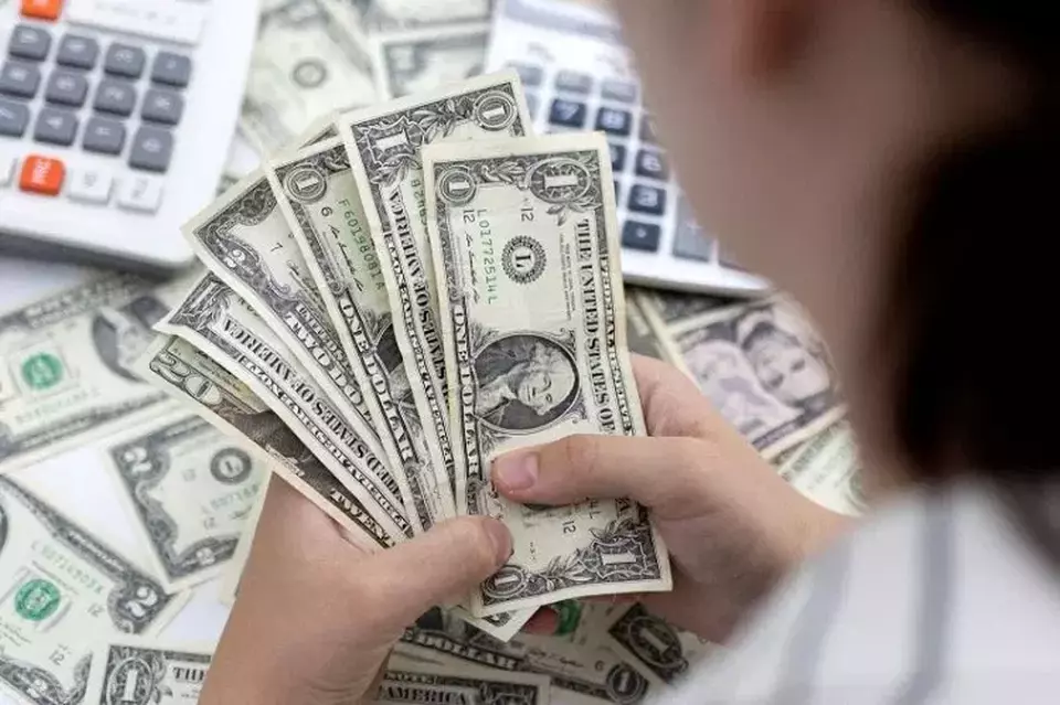 Seorang wanita memegang lembaran uang kertas dolar Amerika Serikat (AS) pada 30 Mei 2022. (FOTO: REUTERS/DADO RUVIC)