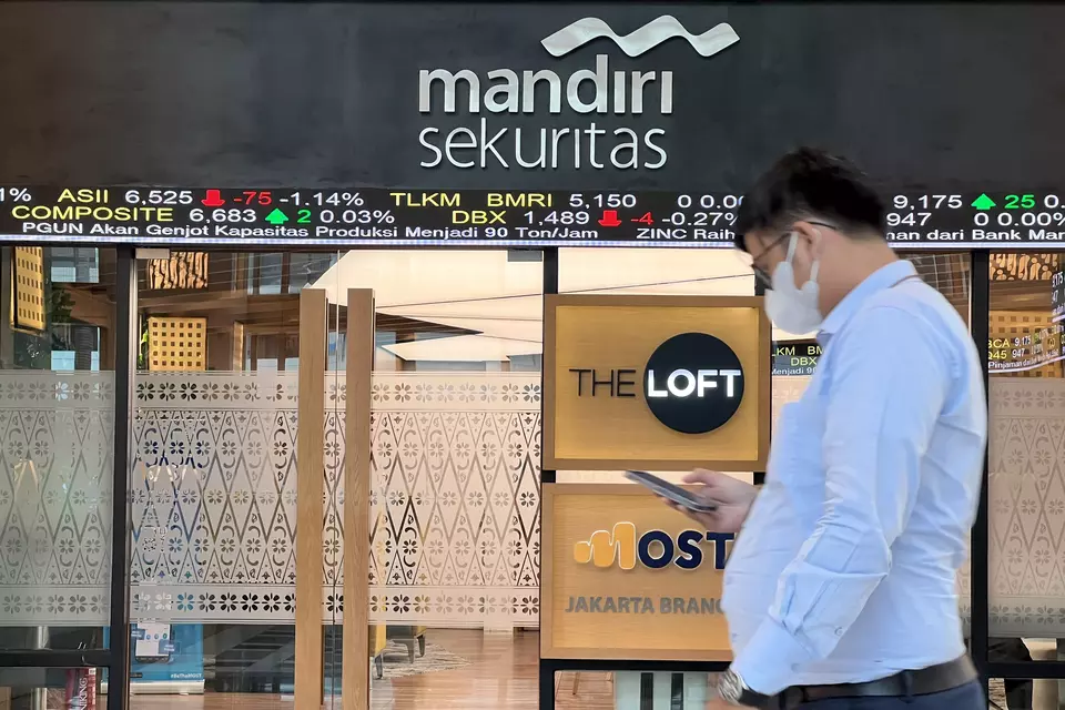Nasabah melintasi layar pergerakan saham. (B-Universe Photo/David Gita Roza)