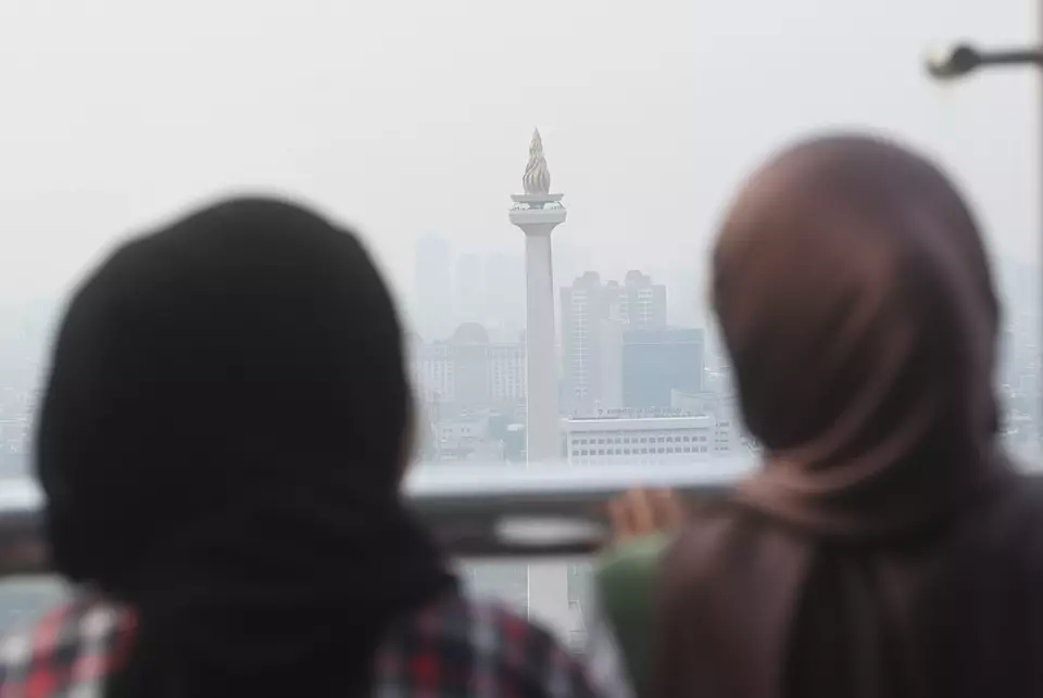 Dua wanita melihat tugu Monas yang tertutup oleh kabut polusi di Jakarta, Selasa (25/7/2023). (ANTARA FOTO/Akbar Nugroho Gumay/nym)